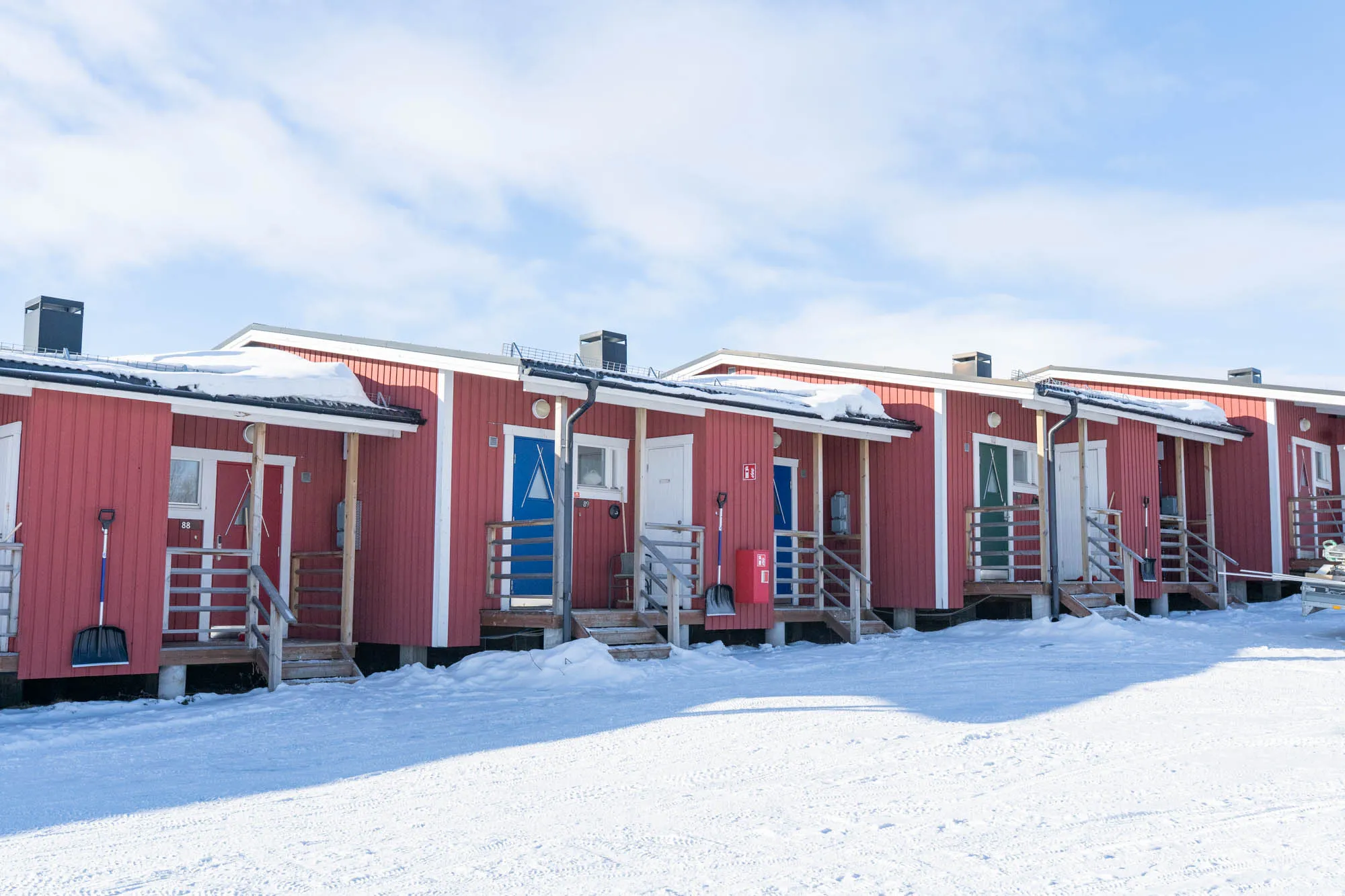 photo of a row of red painted cabins in the snow