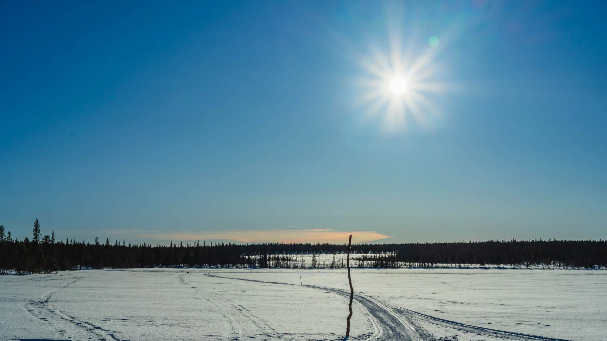 iridescent cloud on top of frozen lake and sun-star