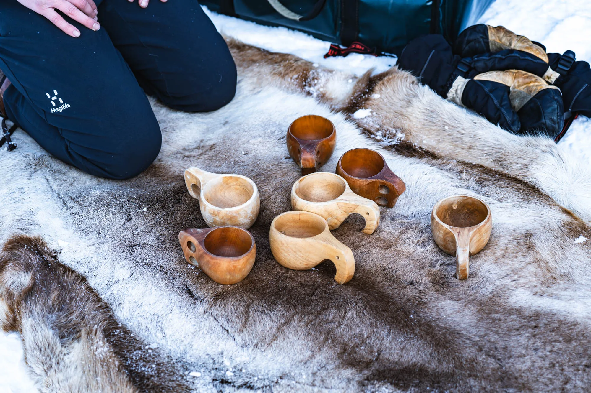 reindeer fur on the floor with person kneeling and an array of empty gluksi cups waiting to be filled