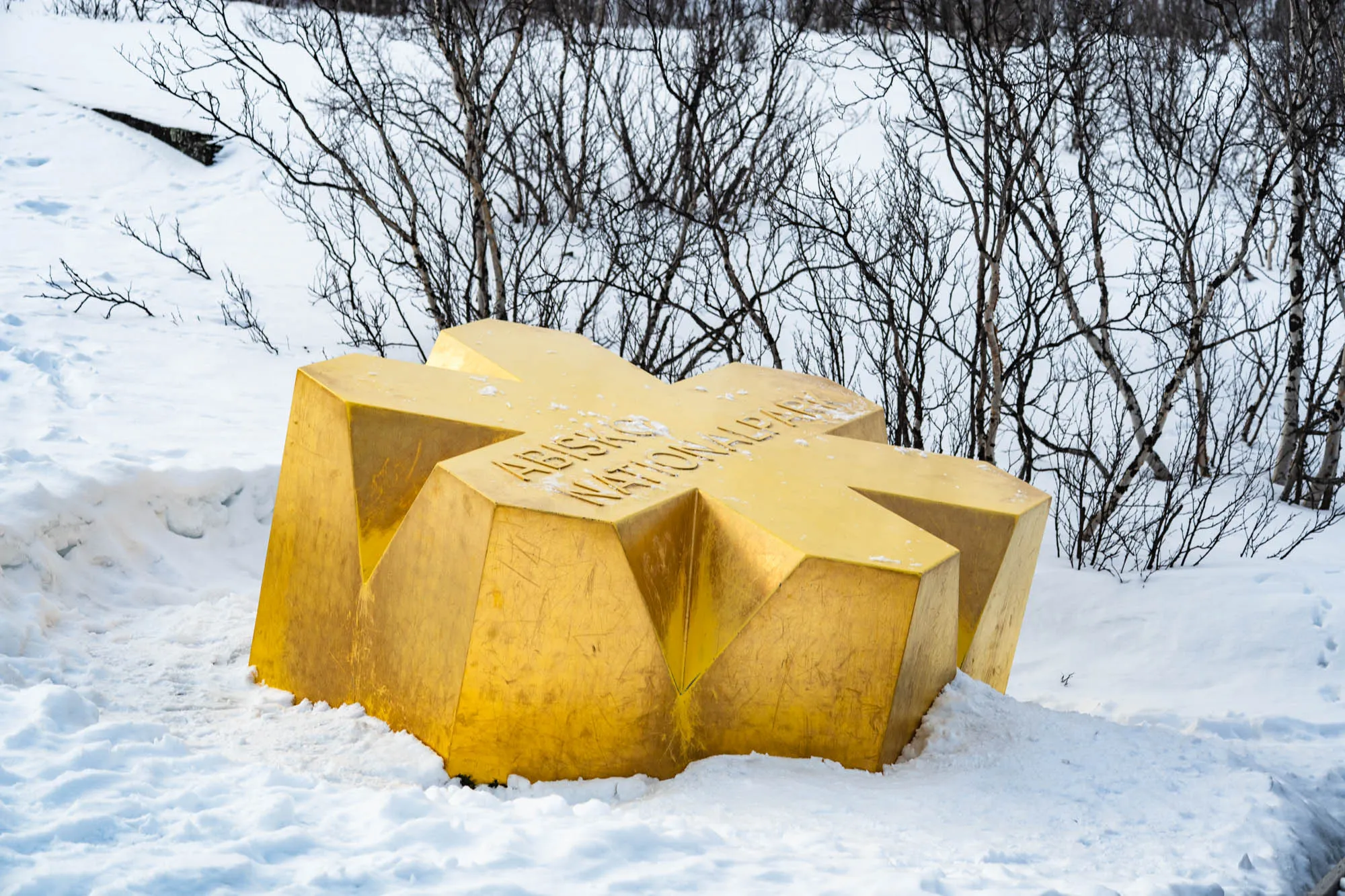 big golden asterisk sculpture in the snow